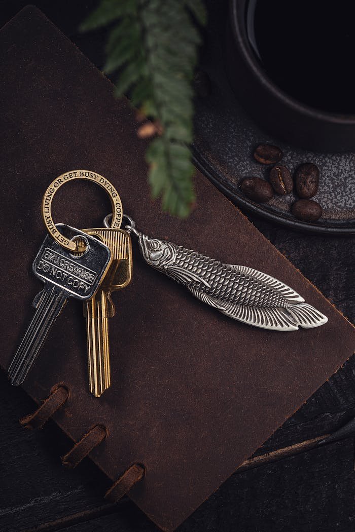 Stylish arowana keychain and keys resting on a rustic journal, paired with coffee beans, creating a vintage aesthetic.